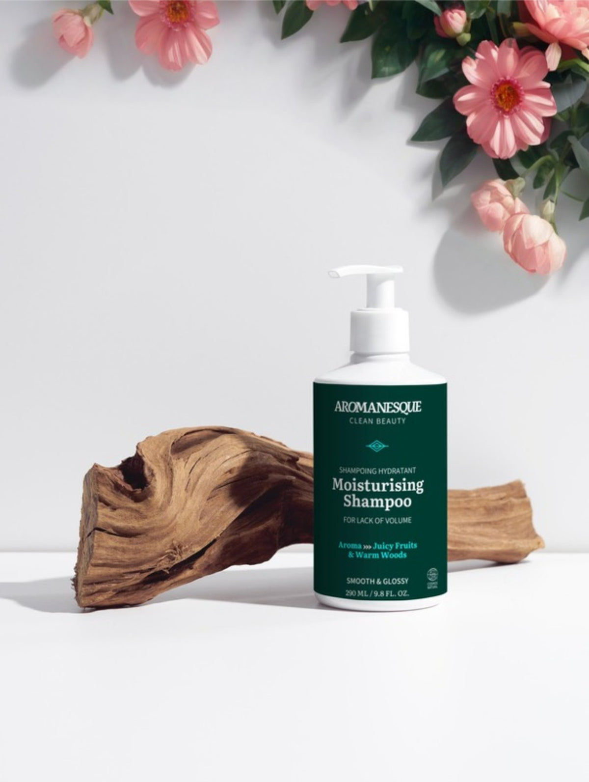Aromanesque shampoo bottle with flowers and wood on a white background