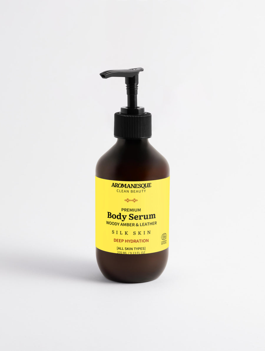 A pump bottle of Aromanesque Premium Body Serum, Woody Amber & Leather scent, against a white background.
